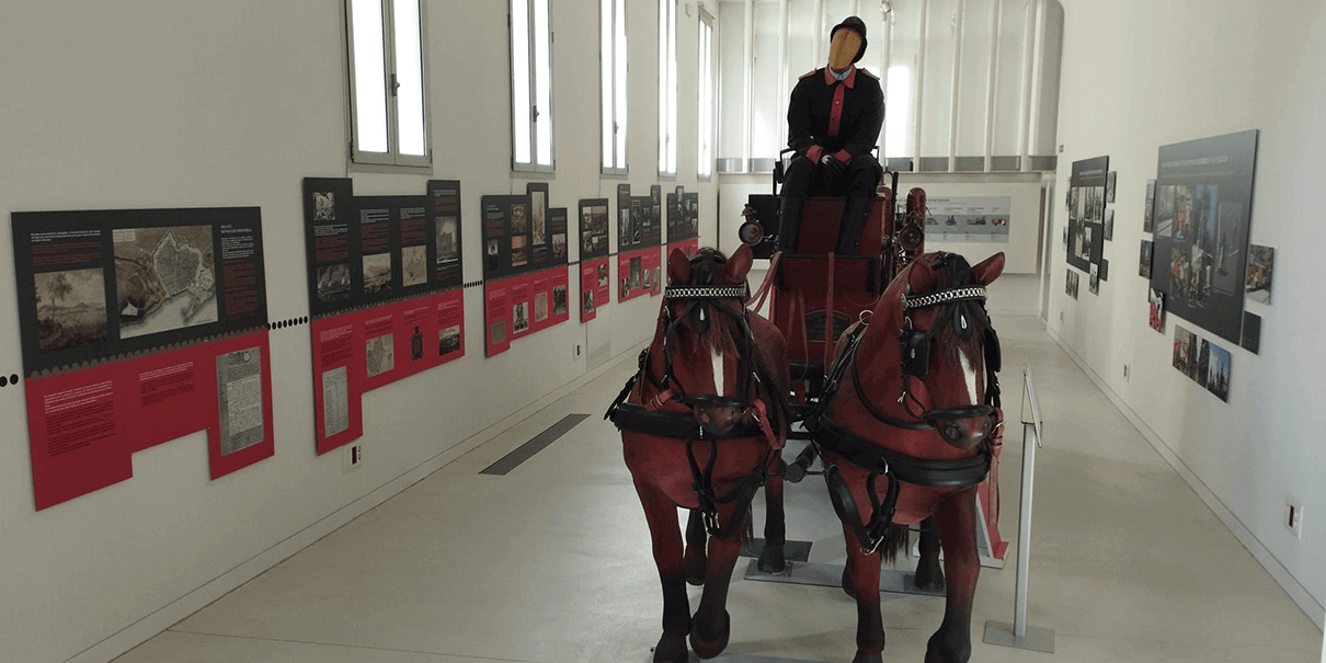 Carro de bomberos con caballos en el centro de la sala de la exposición museográfica del Espai Bombers.